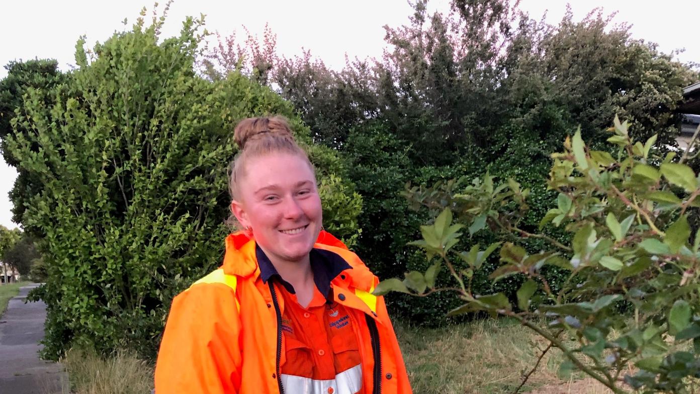 Bekk is outside wearing hi-vis and smiling at the camera.