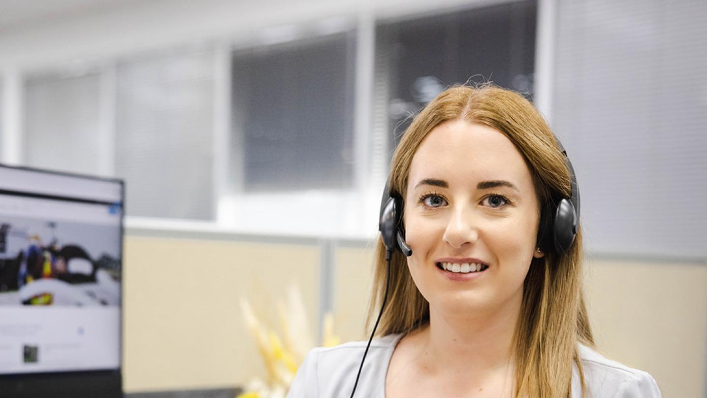 Sarah from our customer service team smiling at the camera wearing her headset.
