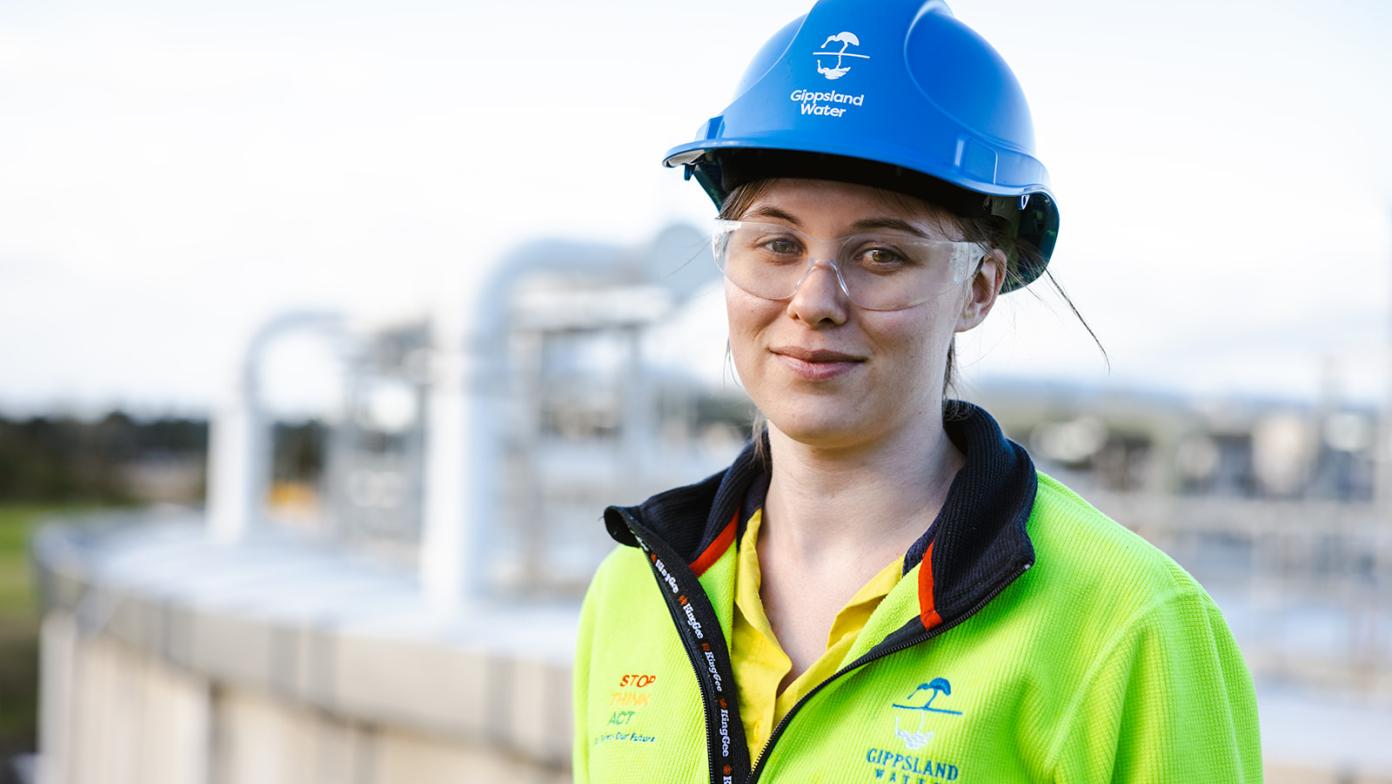 Rowena is wearing a hard hat and safety glasses smilling and looking at the camera.