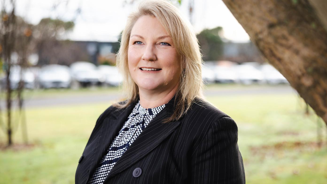 Sarah Cumming smiles, wearing a black suit jacket. 
