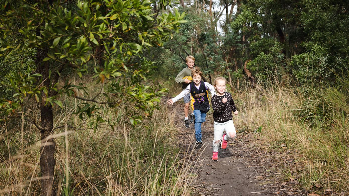 Children walk along a path in bushland.
