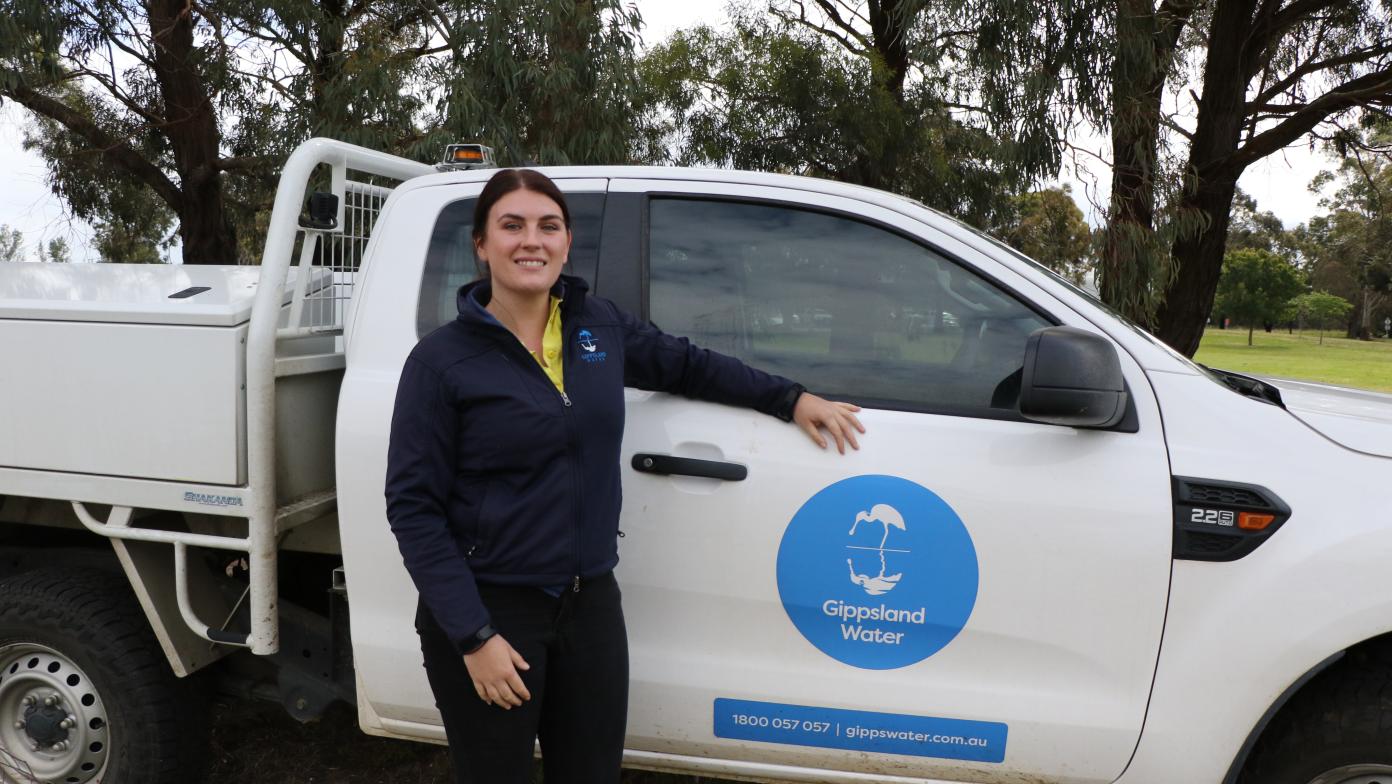 Steph dressed in uniform in front of her work vehicle. She's smiling and looking at the camera.