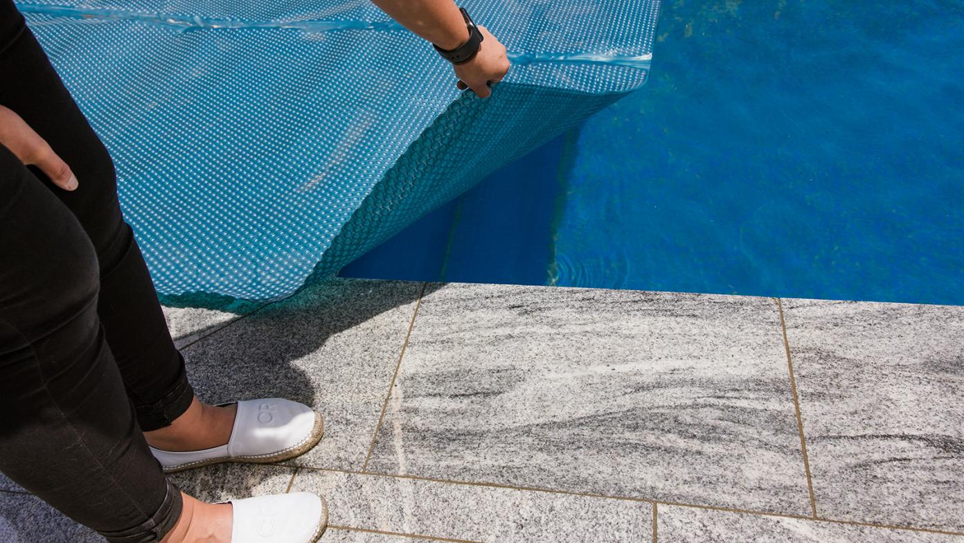 Pool cover being placed over a pool