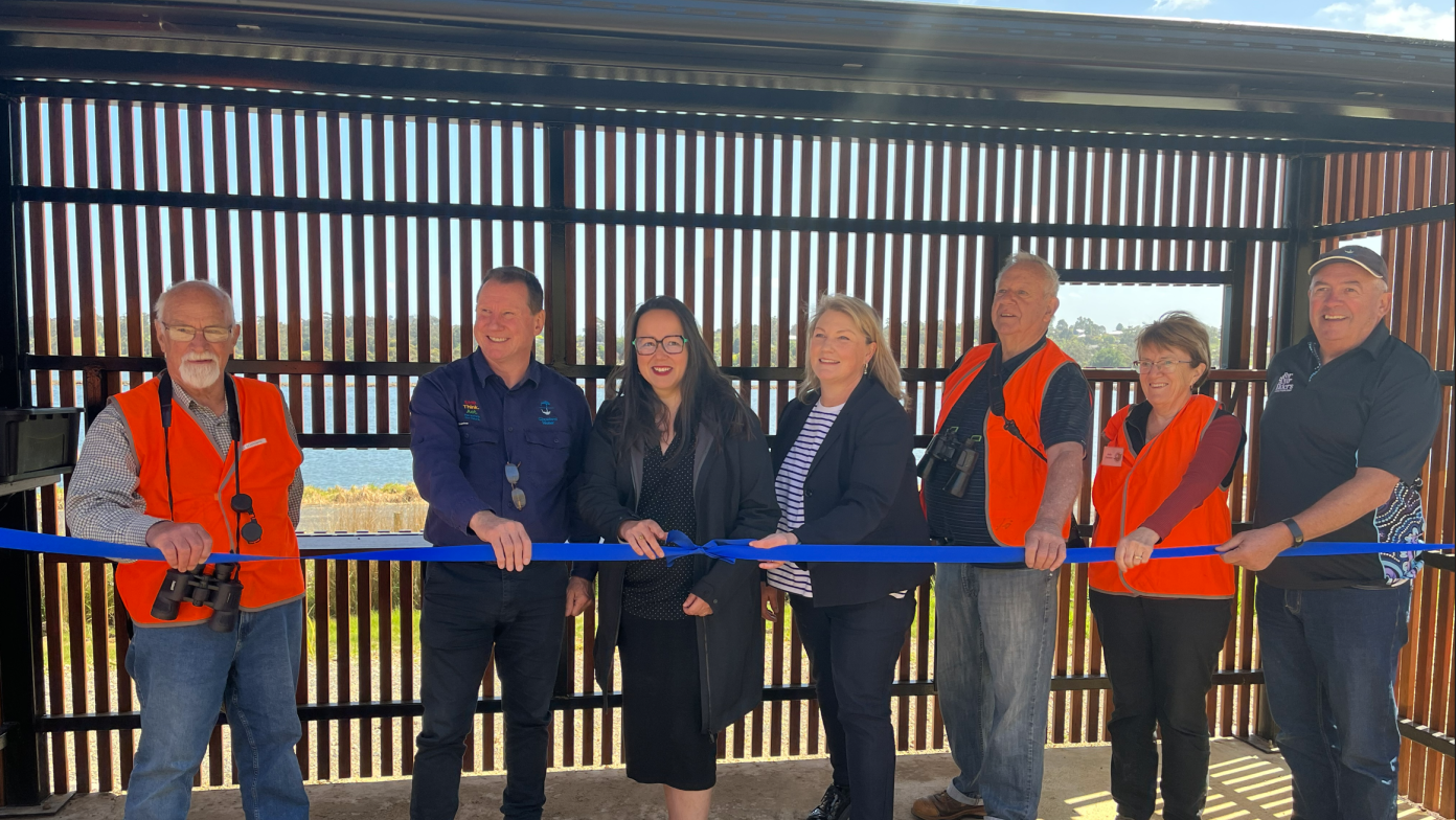 People stand in bird hide behind blue ribbon