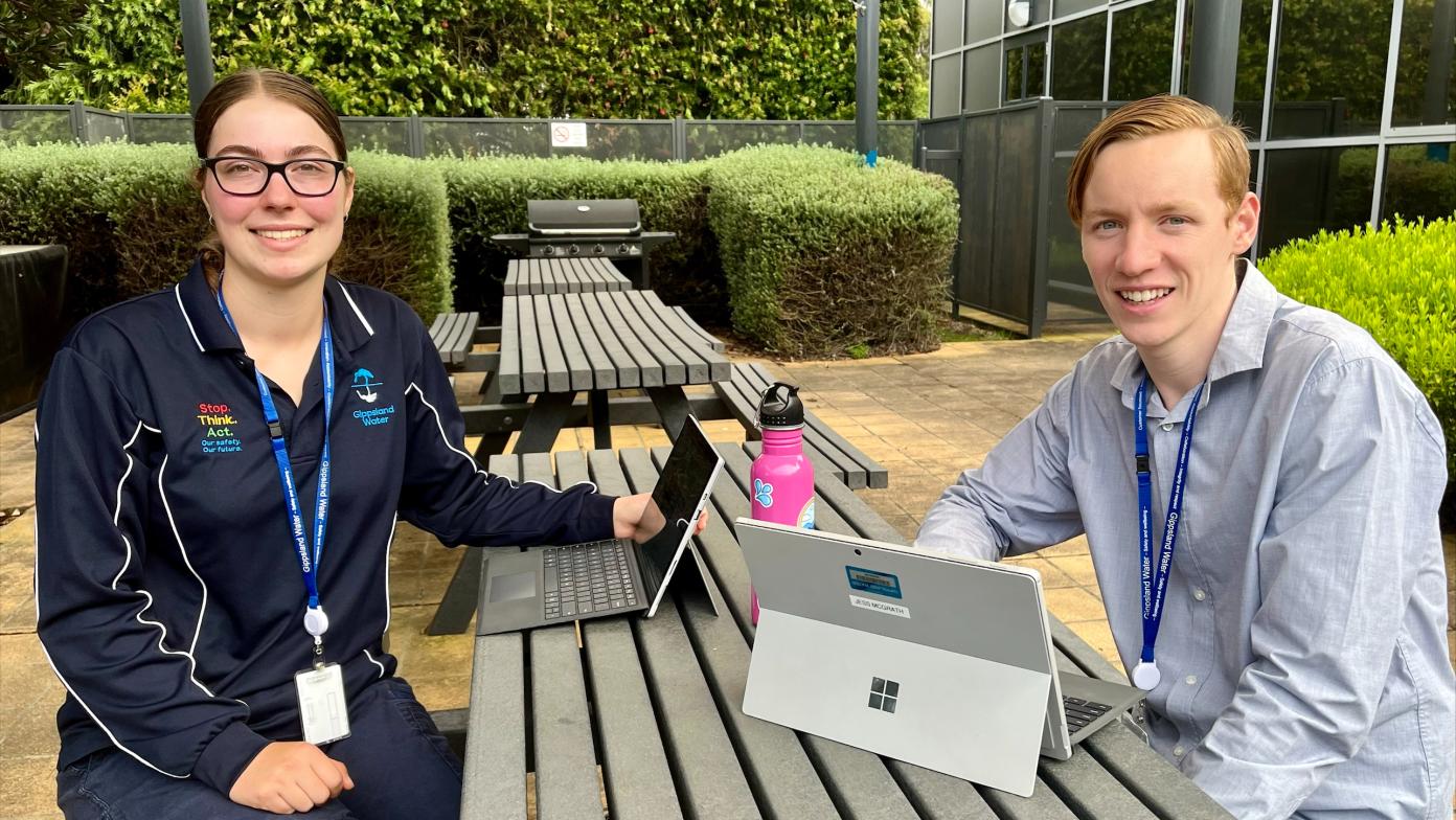 Image of two vacation students sitting at a table and smiling at the camera