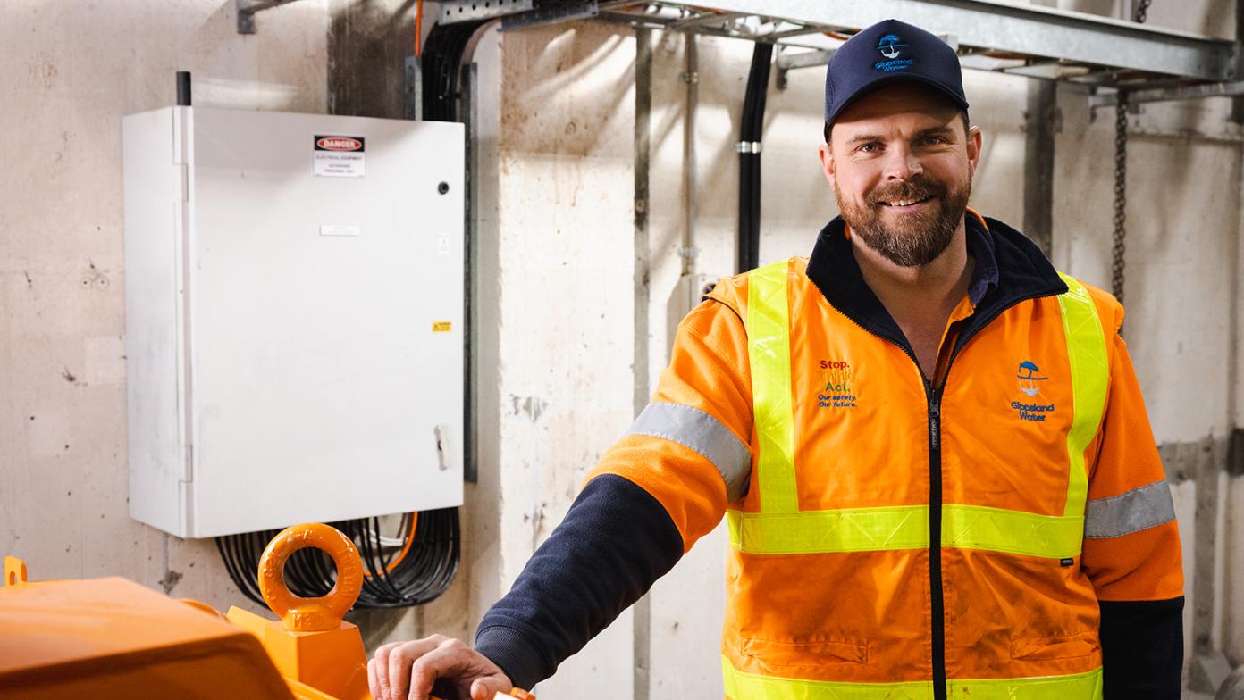 Luke is inside the Tyers pump station. He's wearing hi-vis and smiling looking at the camera.