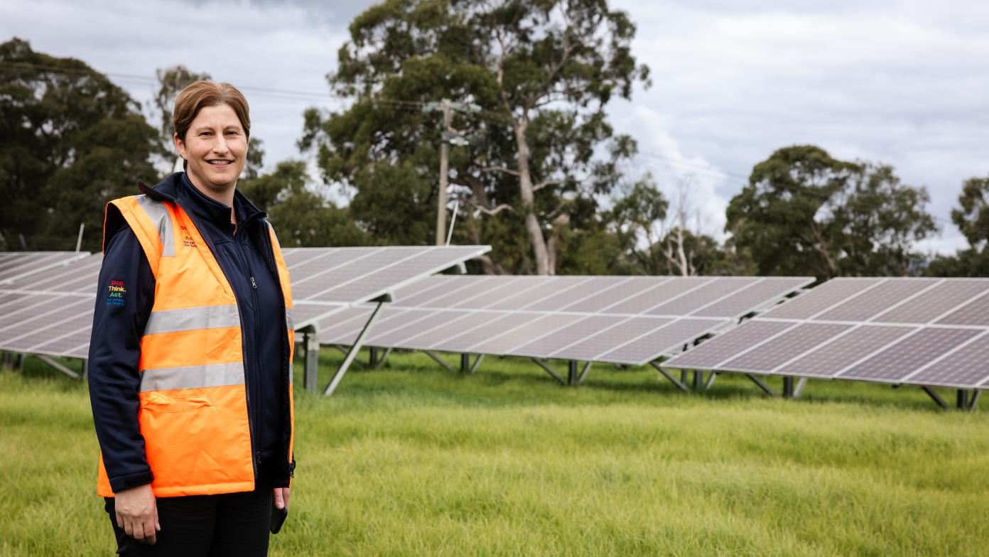 Someone smiling in front of solar panels. 