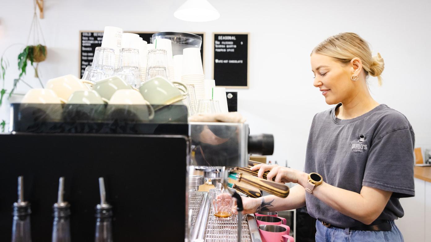 Barista using coffee machine to make a coffee in a cafe
