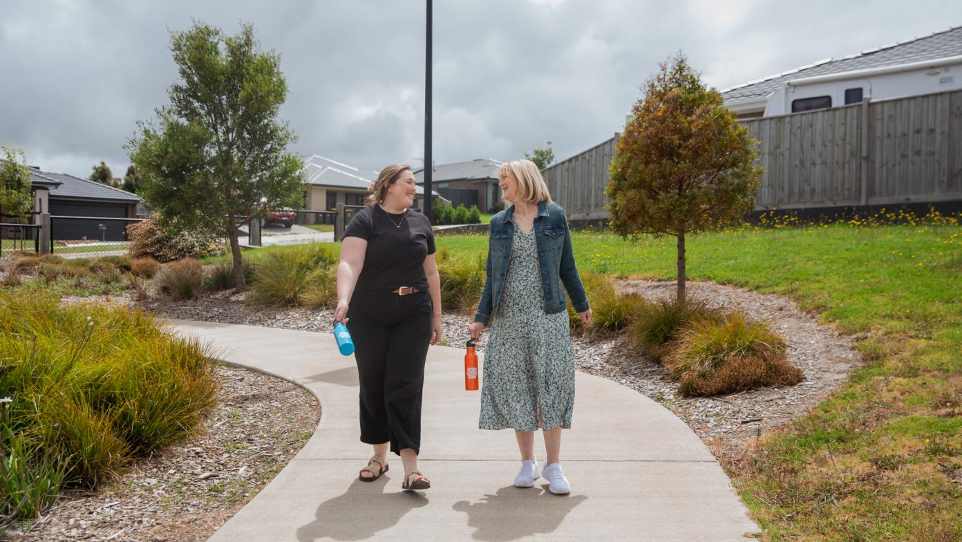 Two people walking in a park holding drink bottles