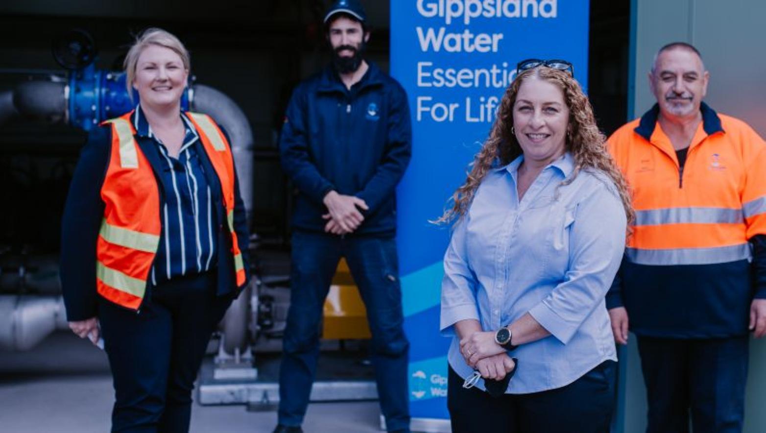 Four people stand in front of Gippsland Water sign