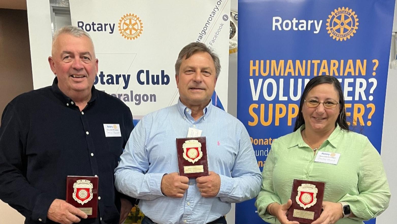 Three people hold awards 