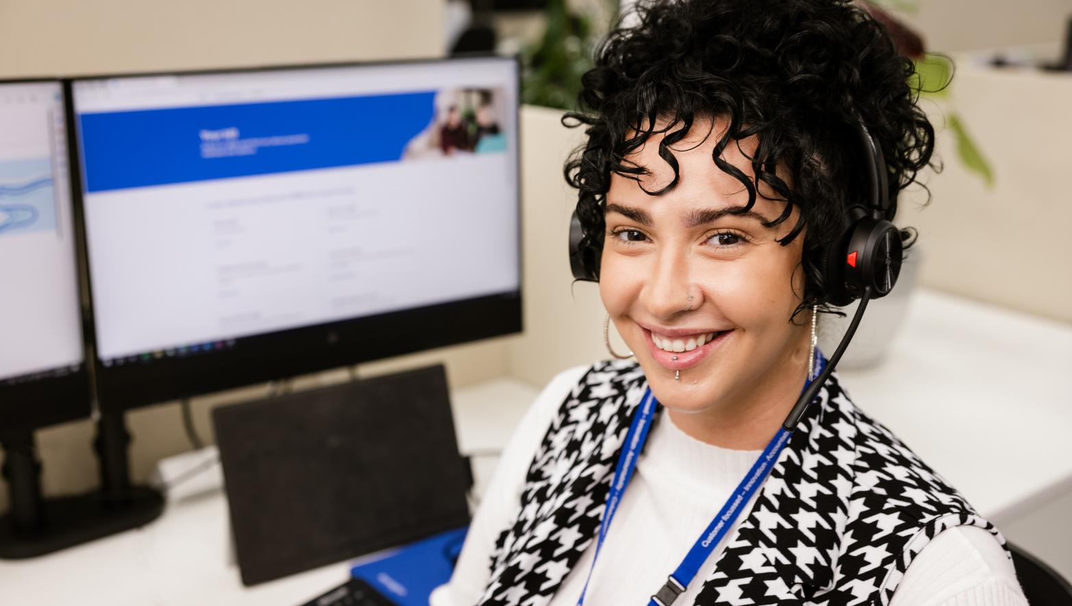 Customer Service representative wearing a headset sitting at their computer smiling