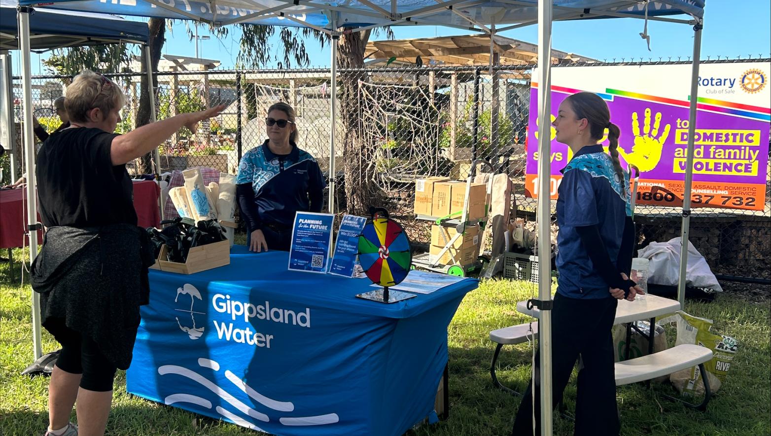Gippsland Water employees stand under the marquee talking to a customer at the Wellington Sustainability festival 