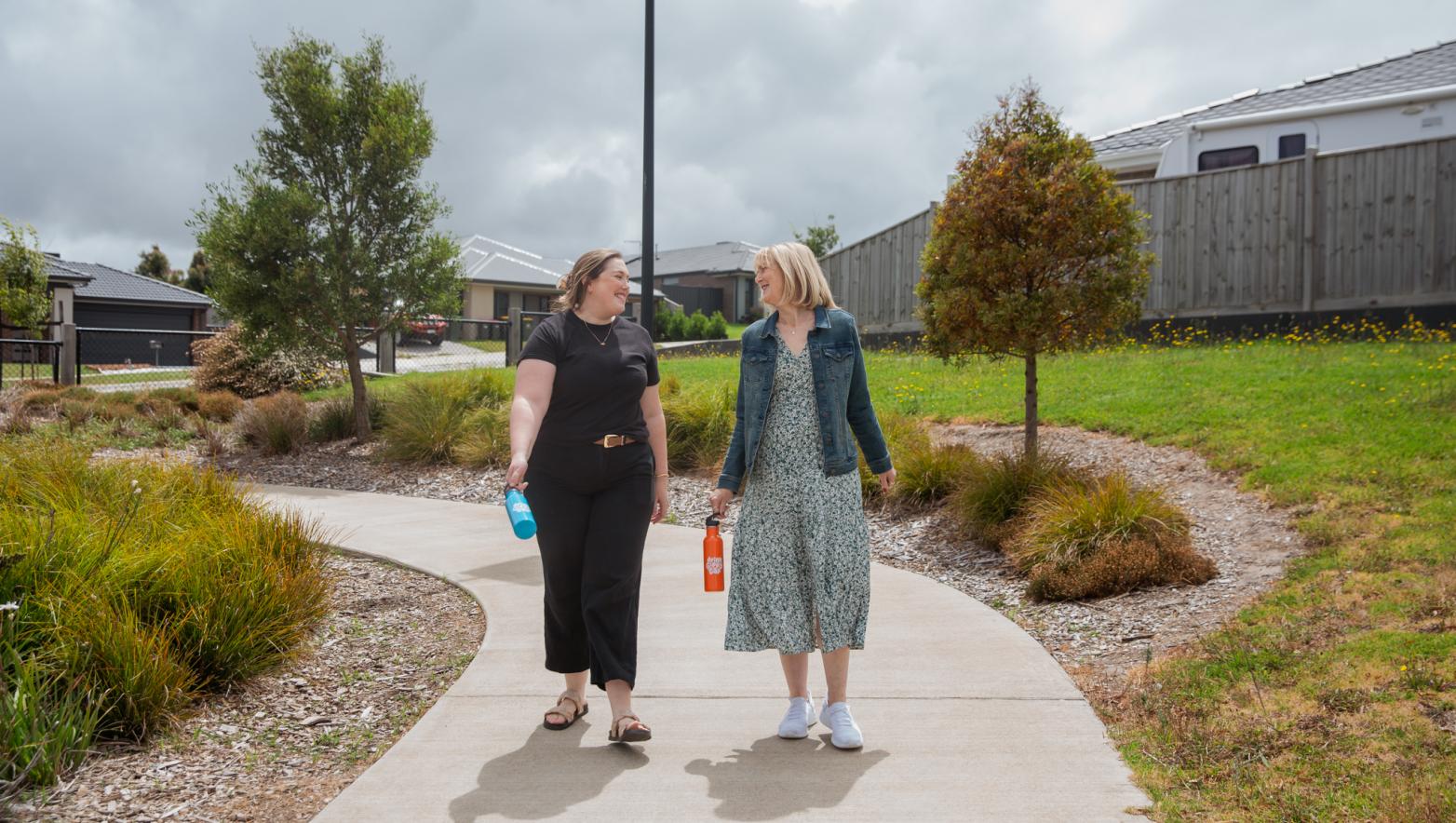 Two people walking in a park holding drink bottles