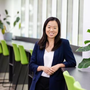 A women looking at the camera smiling casually leaning on the table