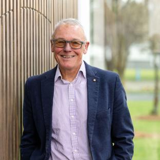 Board Chair smiling and posing against a textured wall